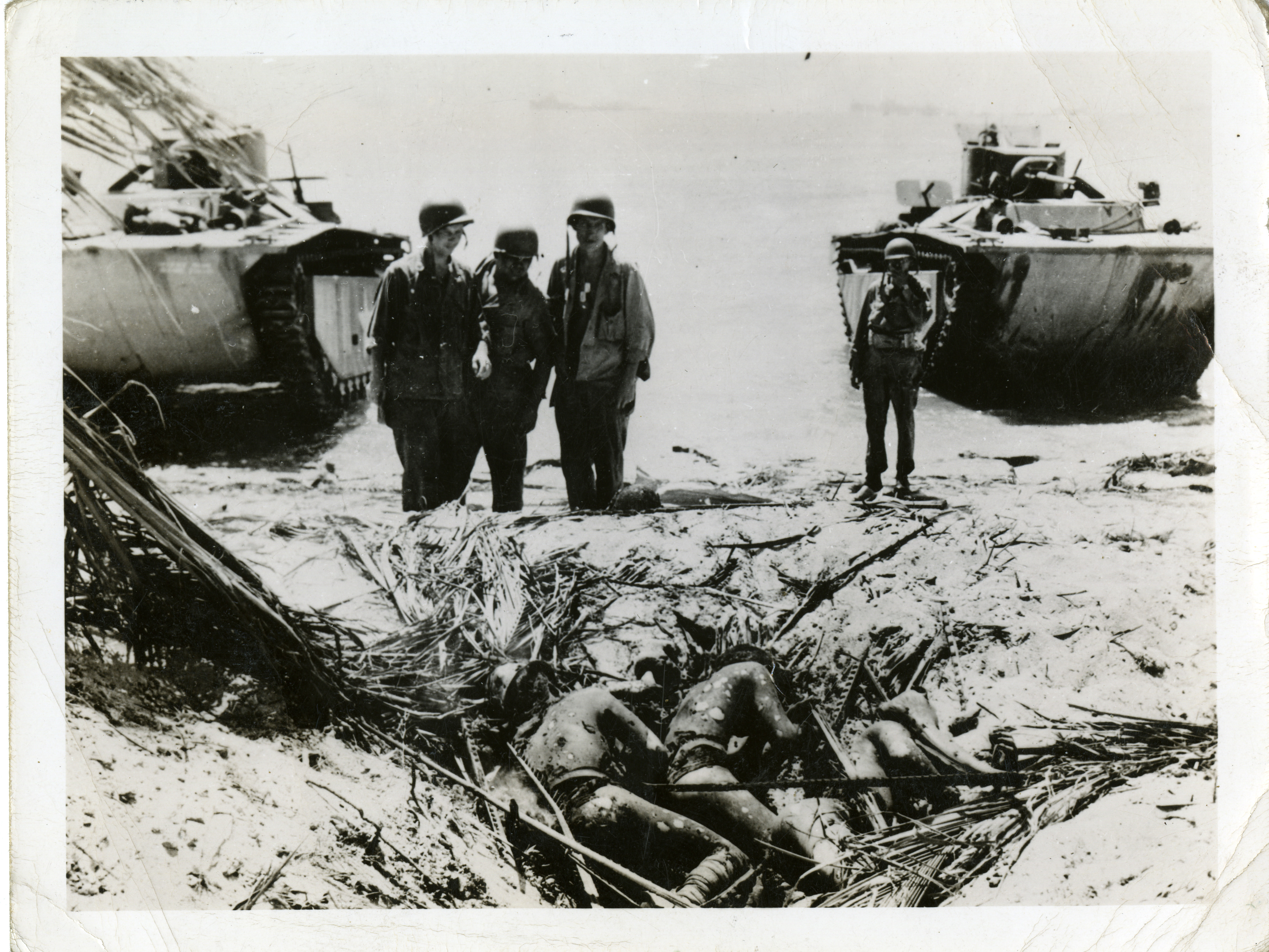 Four Us Marines Stand On A Beach Over The Bodies Of Dead Japanese