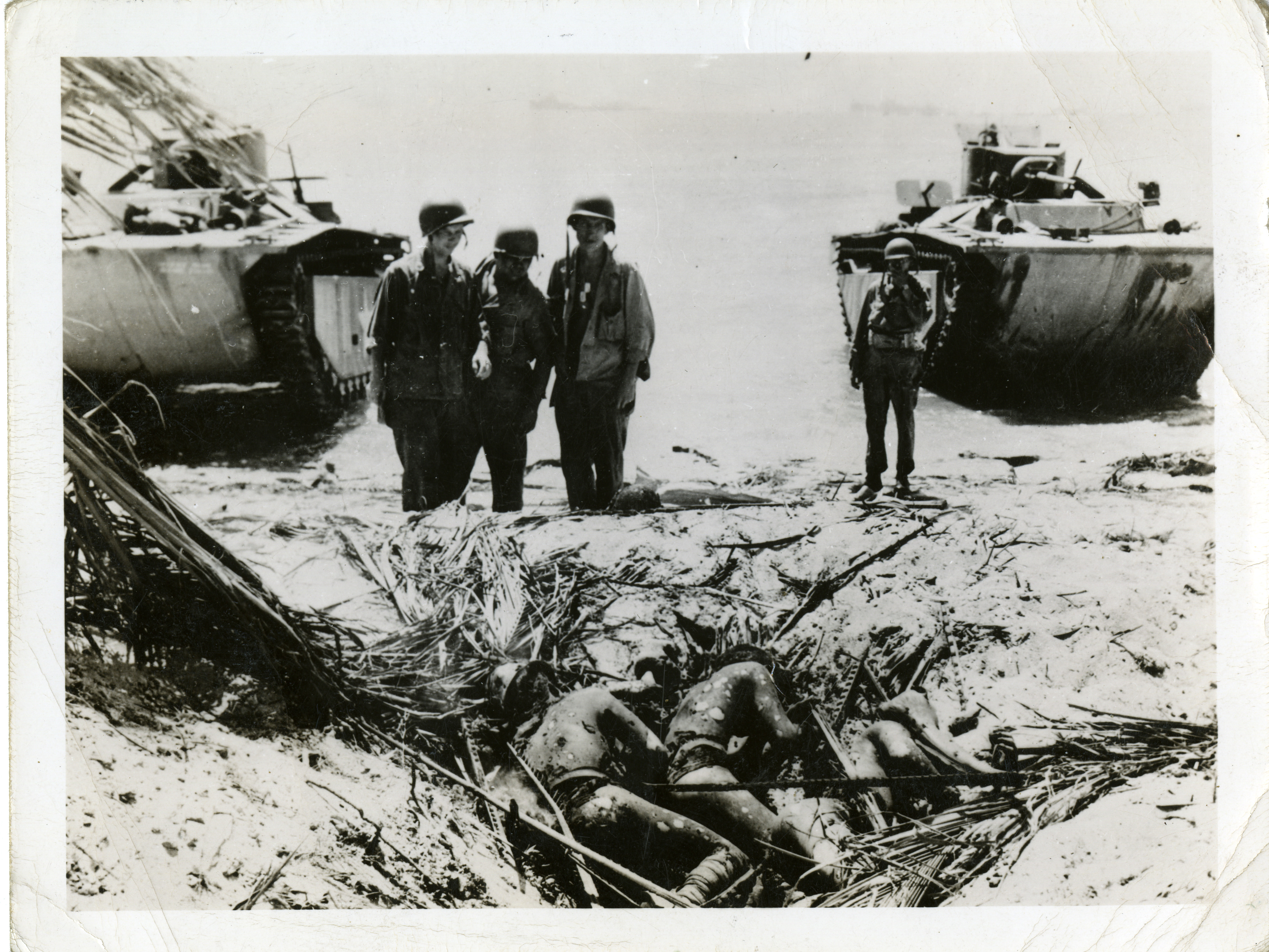 four-us-marines-stand-on-a-beach-over-the-bodies-of-dead-japanese