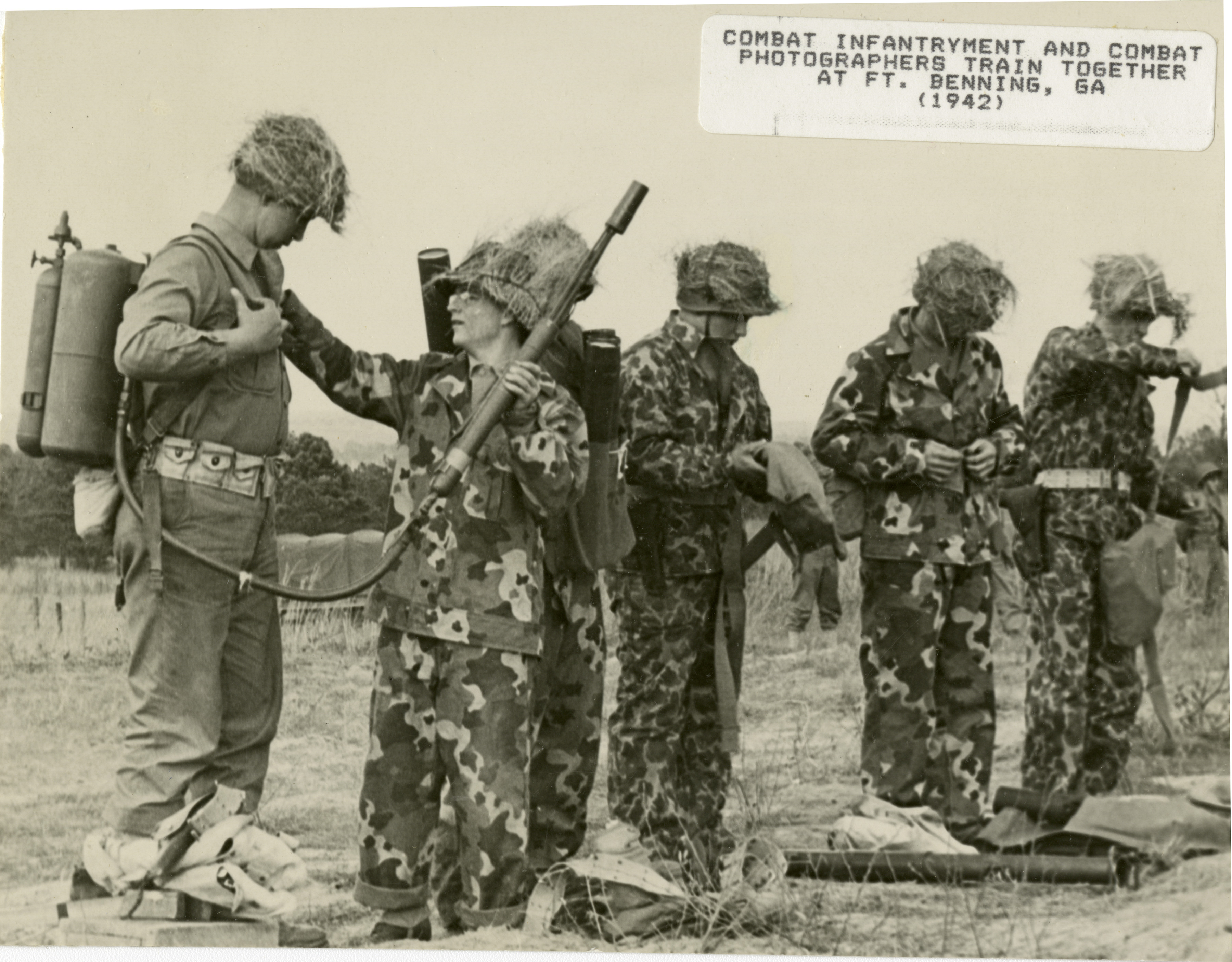 Six soldiers suiting up, some in a camouflage pattern not used during ...