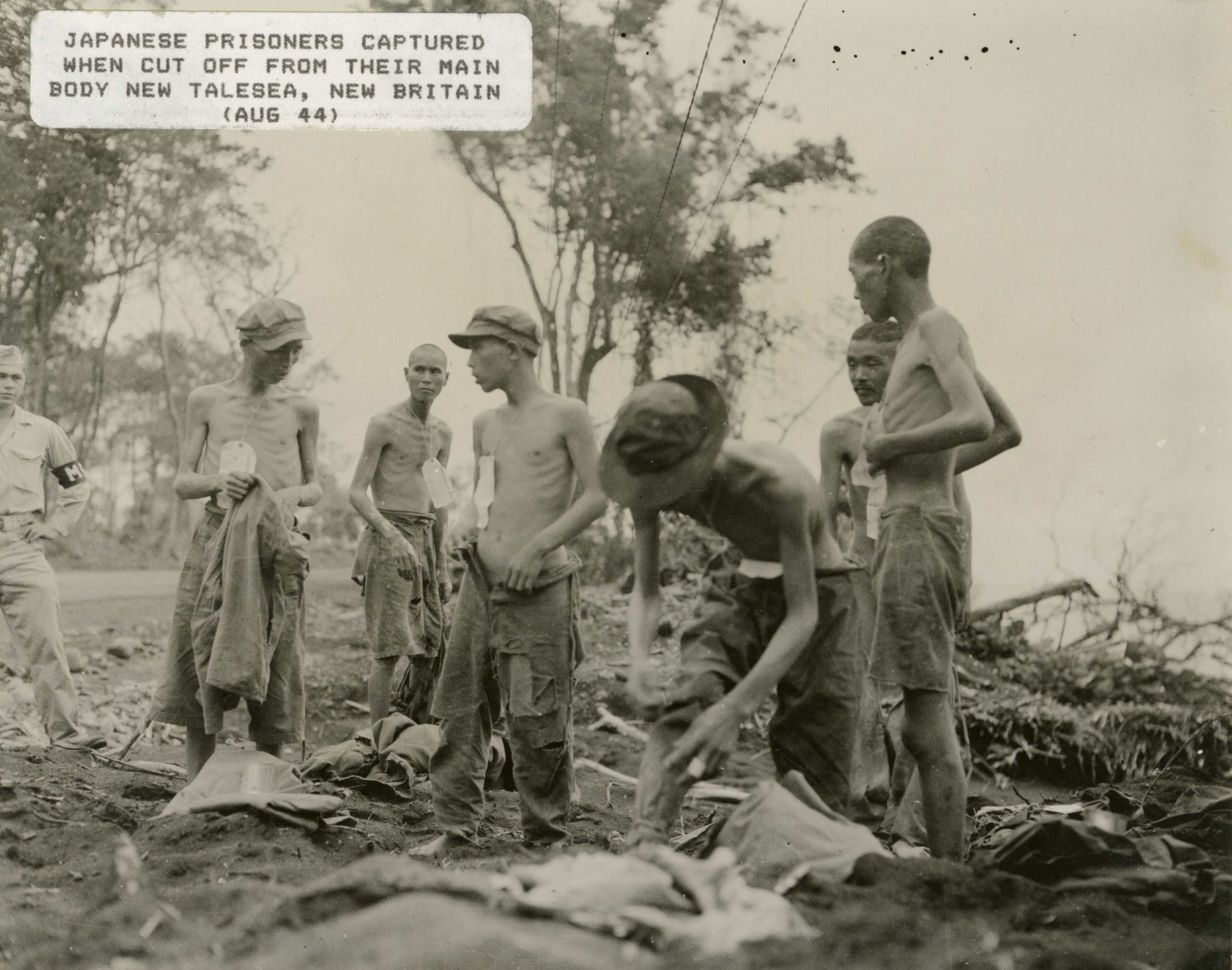 Six Emaciated Japanese Prisoners Of War Are Overseen By An MP At 