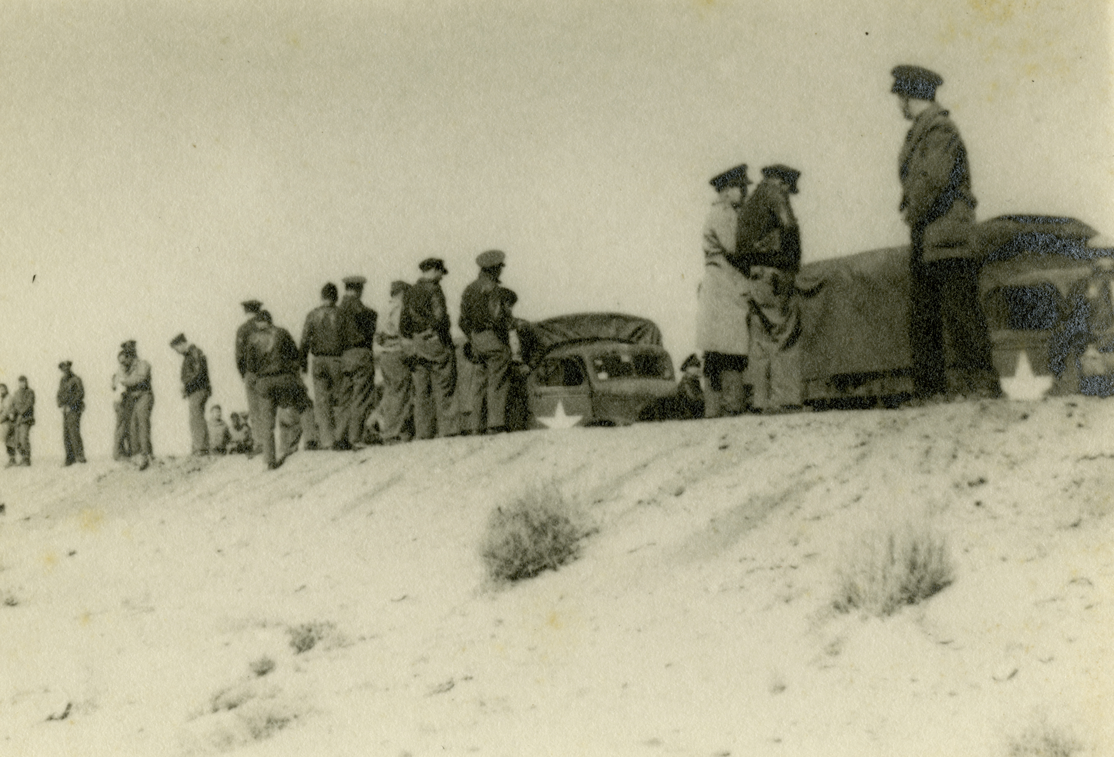 USAAF personnel stand along the side of a road near two 2- ton trucks ...