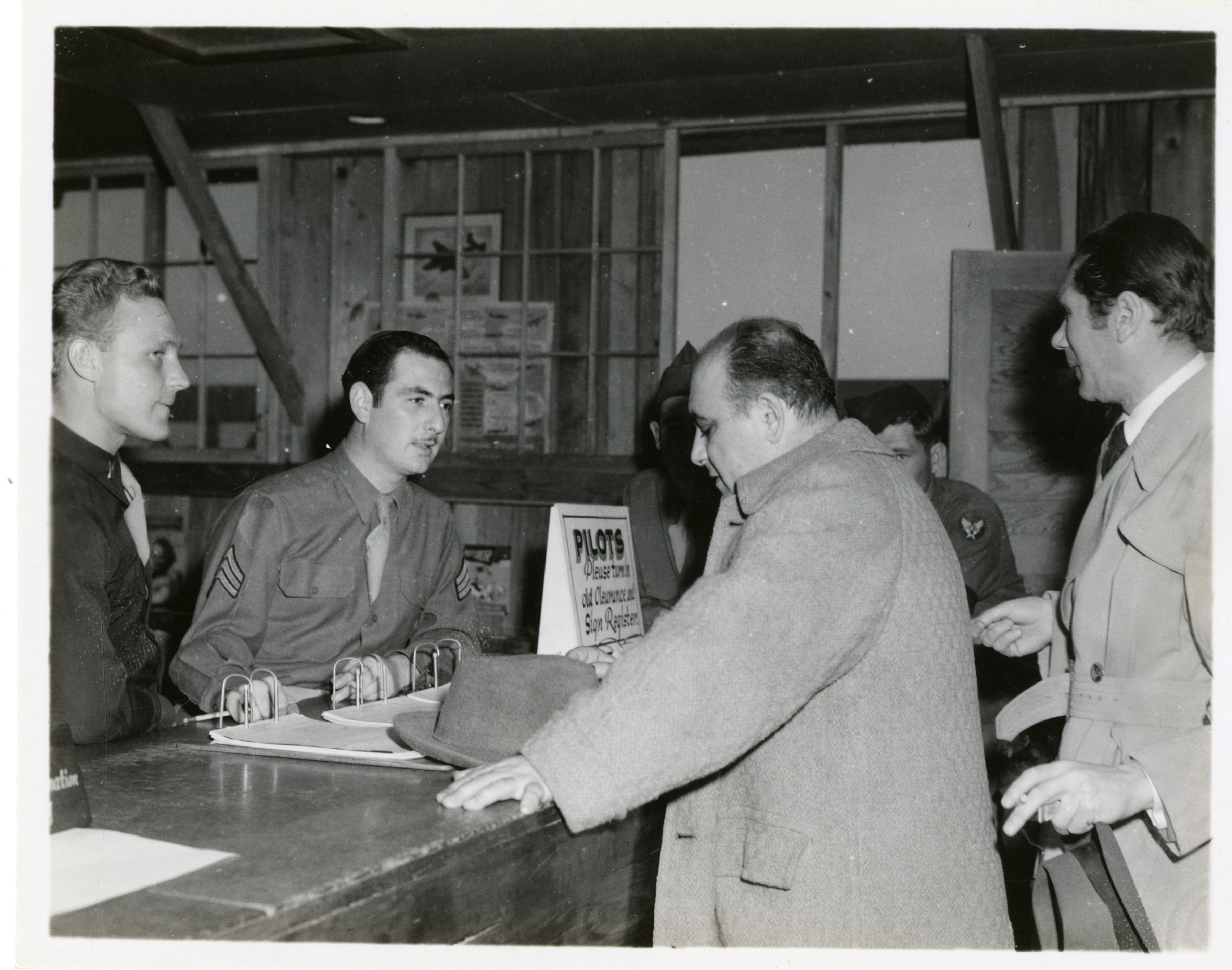 Civilian Men In Overcoats At Registration Desk Of The Abeline