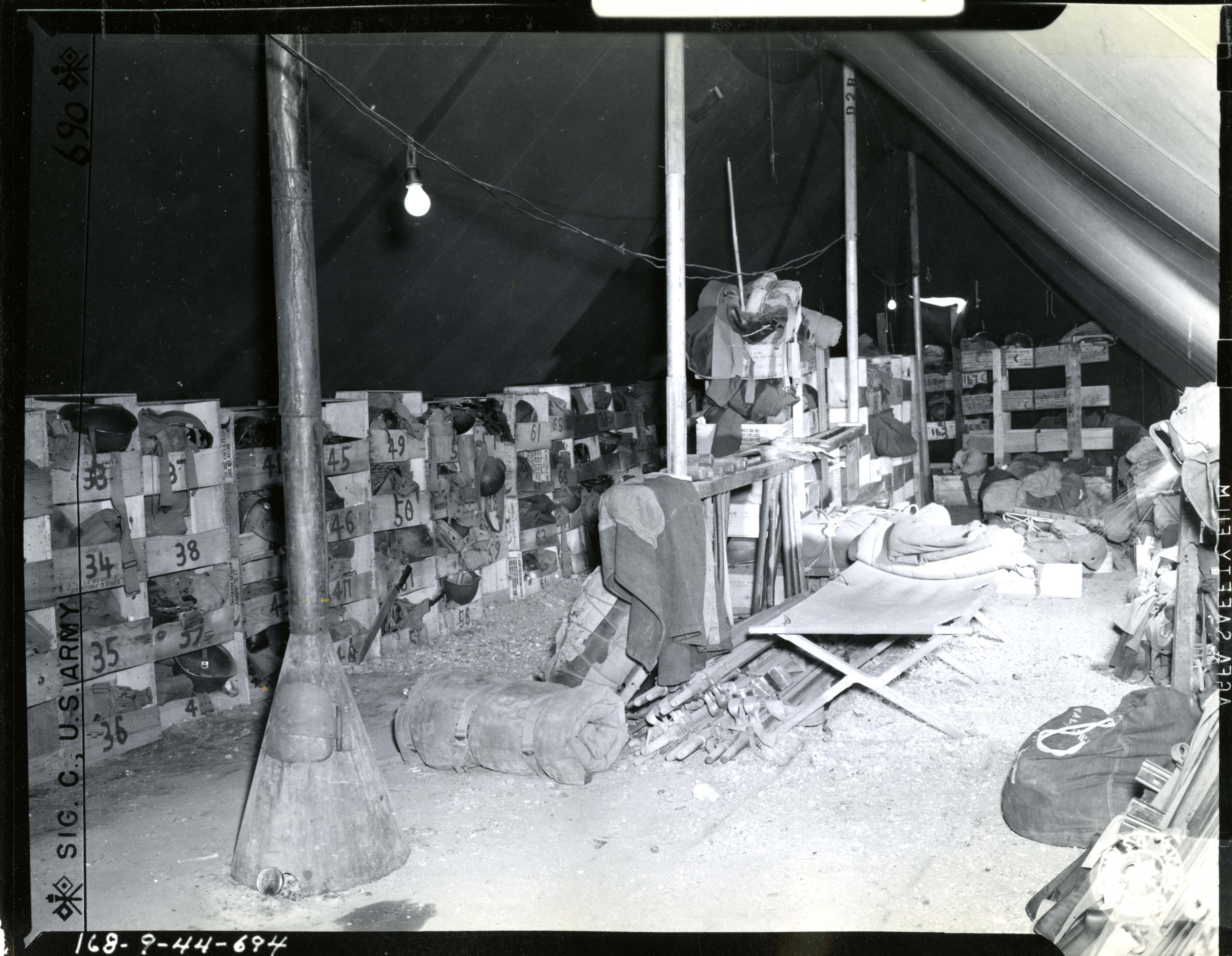Interior of tent where barracks bags field packs, rifles and other